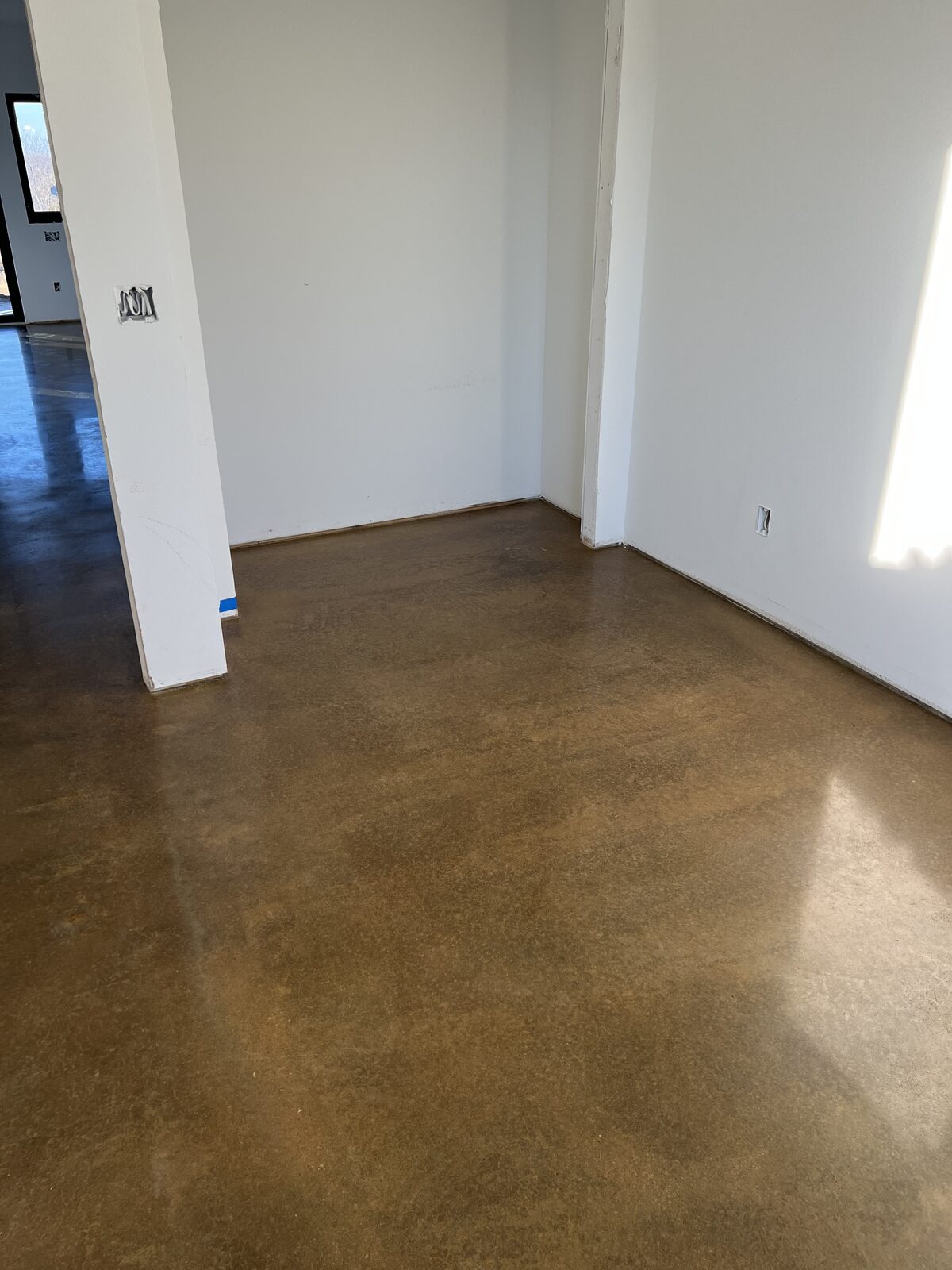 Polished concrete floor with a warm stained finish in a new build